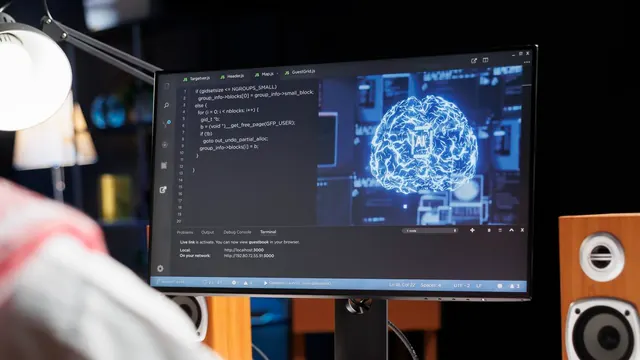 Developer at a desktop screen showing code and an AI brain graphic (stock photo, illustrative)